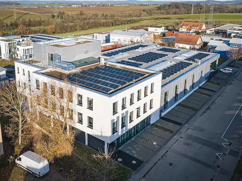Luftaufnahme eines Gewerbebetriebs mit begrüntem Dach und Solarmodulen von PUR Projektbau.