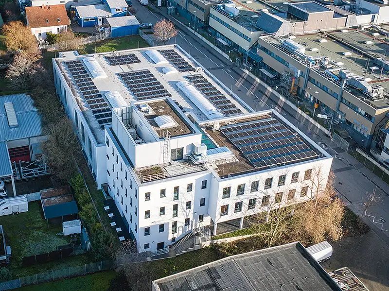 Luftaufnahme eines Gewerbebetriebs mit begrüntem Dach und Solarmodulen von PUR Projektbau.
