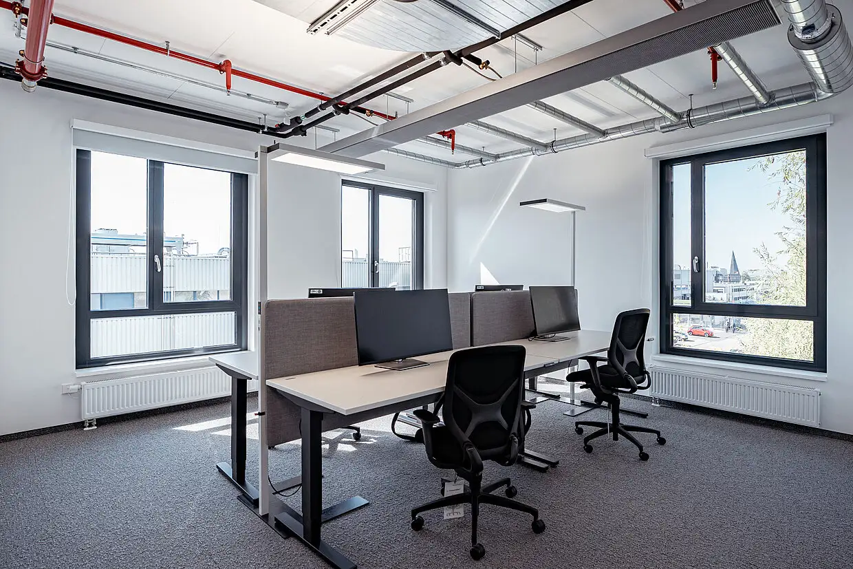 Moderner Großraumbüro-Arbeitsplatz mit minimalistischen Schreibtischen in einer Industrie-Zentrale.