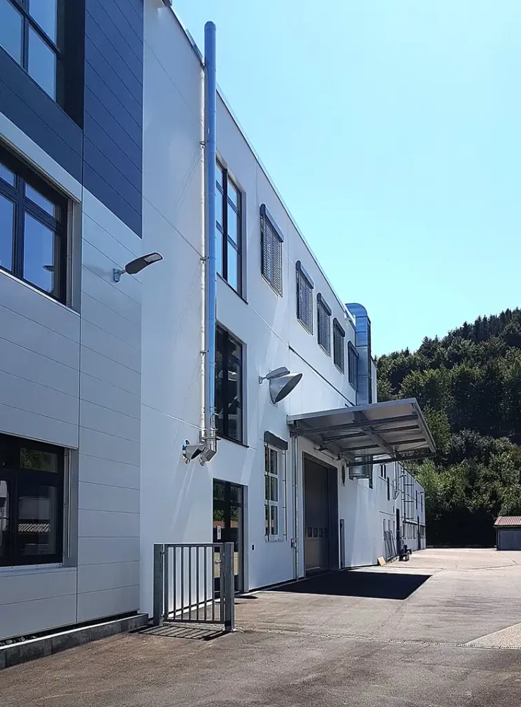 Zweistöckiges, weißes Büro- und Industriegebäude mit modernen Fensterfronten.
