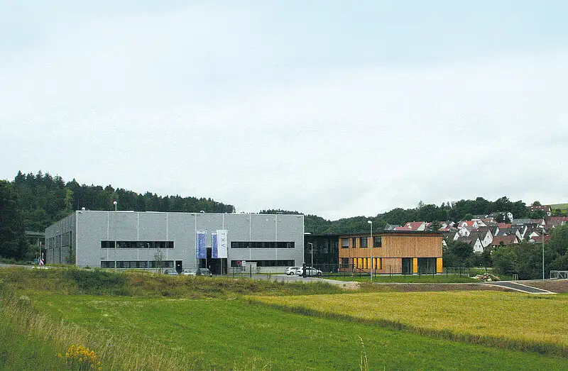 Modernes Industriegebäude von PUR Projektbau auf einem grünen Grundstück unter blauem Himmel.