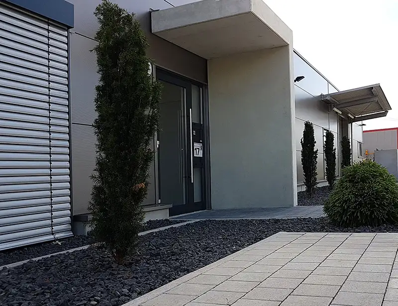 Eingangsbereich eines modernen PUR Projektbau Gebäudes mit Begrünung im Außenbereich.