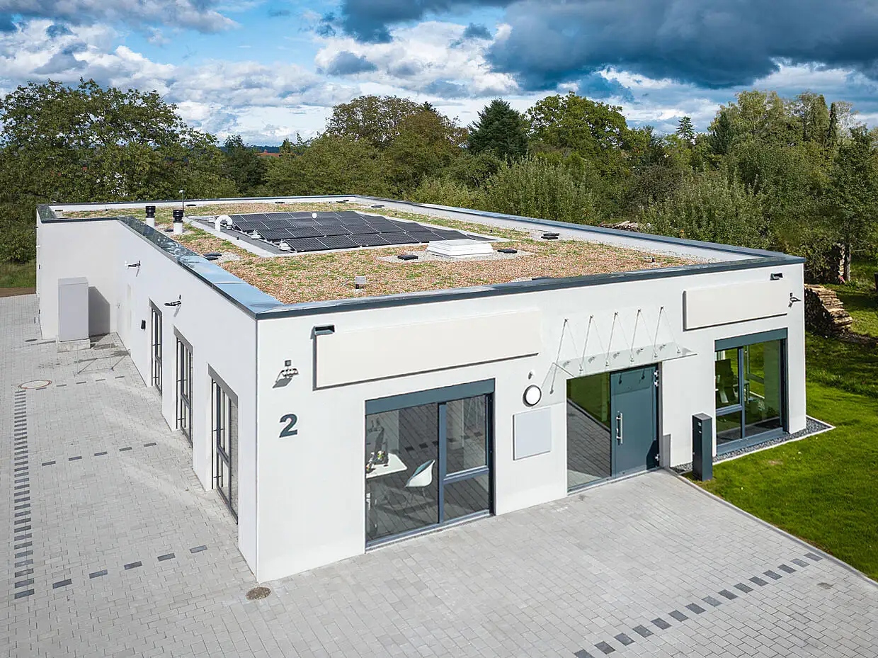 Moderne Industrie- und Gewerbe-Architektur mit Sektionaltor und Außenbeleuchtung von PUR Projektbau.