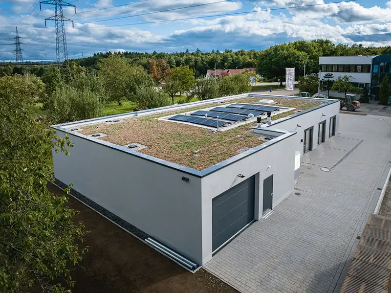 Schräge Außenansicht eines modernen Gewerbe-Gebäudes mit integriertem Garagentor und begrüntem Dach.