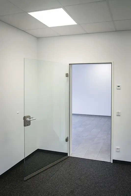 Minimalistischer Innenraum mit einer Glastür in einem neu gebauten Gebäude.