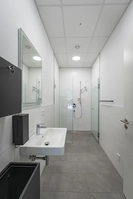 Modernes, minimalistisches Badezimmer in Weißgrau für Mitarbeiter in einem Gewerbe-Gebäude von PUR Projektbau.