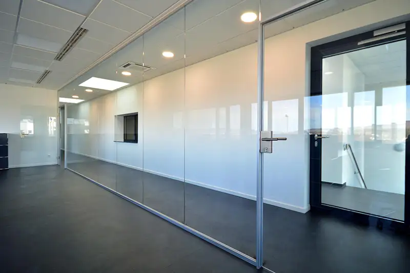 Langer Flur im Bürogebäude mit großen Glasfronten und hellem Licht.