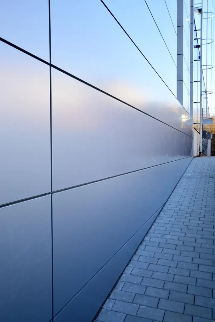 Glatte, graue Metallfassade eines modernen Industriegebäudes in der Nahaufnahme.