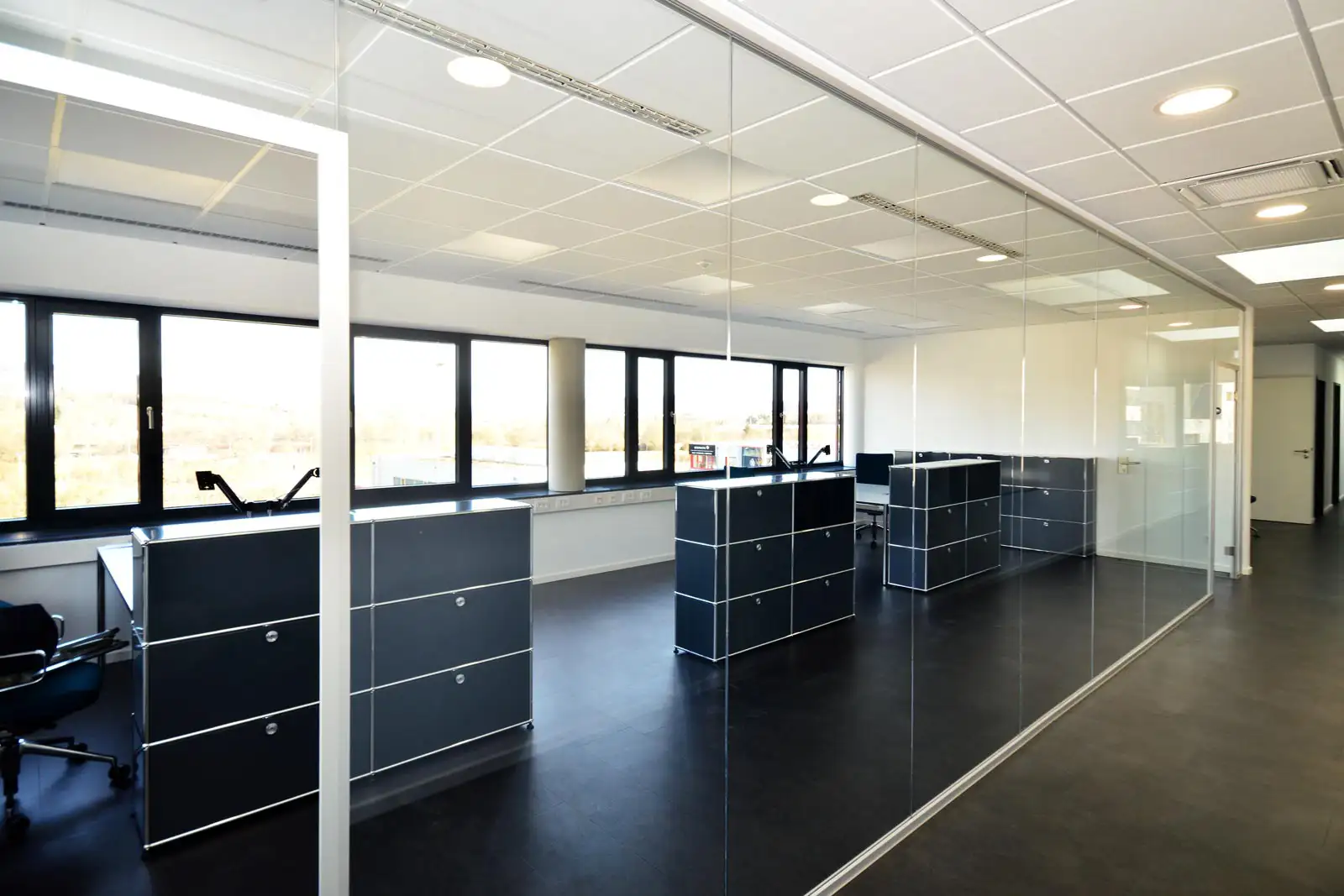 Blick durch eine Glaswand in ein modern möbliertes Büro in einem PUR Projektbau Gebäude.
