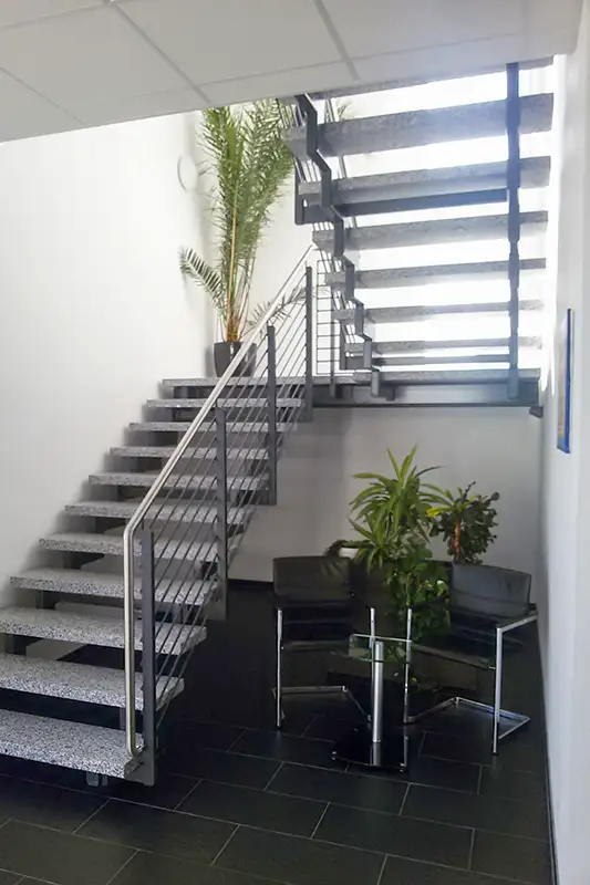 Elegante Innentreppe aus Stahl und Holz in einem modernen Büro- und Industriegebäude.