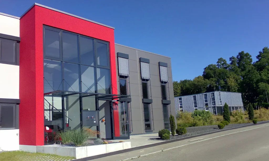 Eingangsbereich eines Gewerbegebäudes mit auffälliger roter Fassadengestaltung von PUR Projektbau.