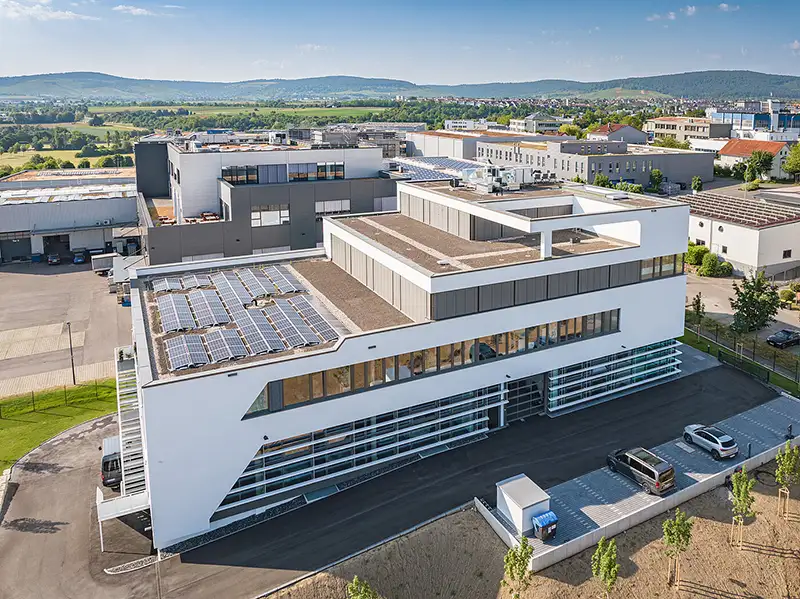 Ein modernes Gewerbegebäude mit Flachdach und Solaranlagen aus der Vogelperspektive, gebaut von PUR Projektbau.