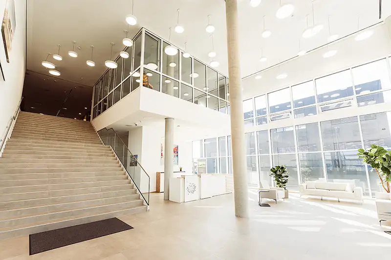 Helles, offenes Foyer mit Treppenaufgang in einem von PUR Projektbau realisierten Industrie- und Gewerbebau.