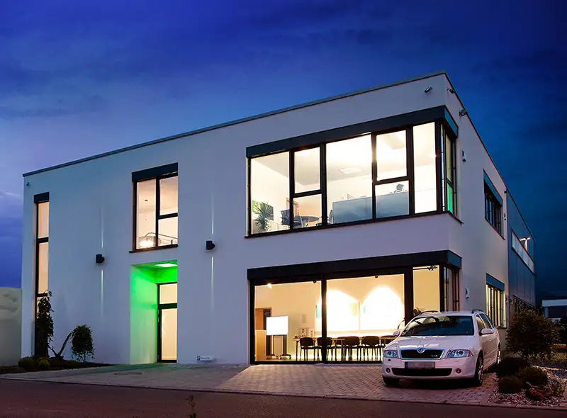 Modernes Bürogebäude von PUR Projektbau bei Nacht mit beleuchteten Fenstern.