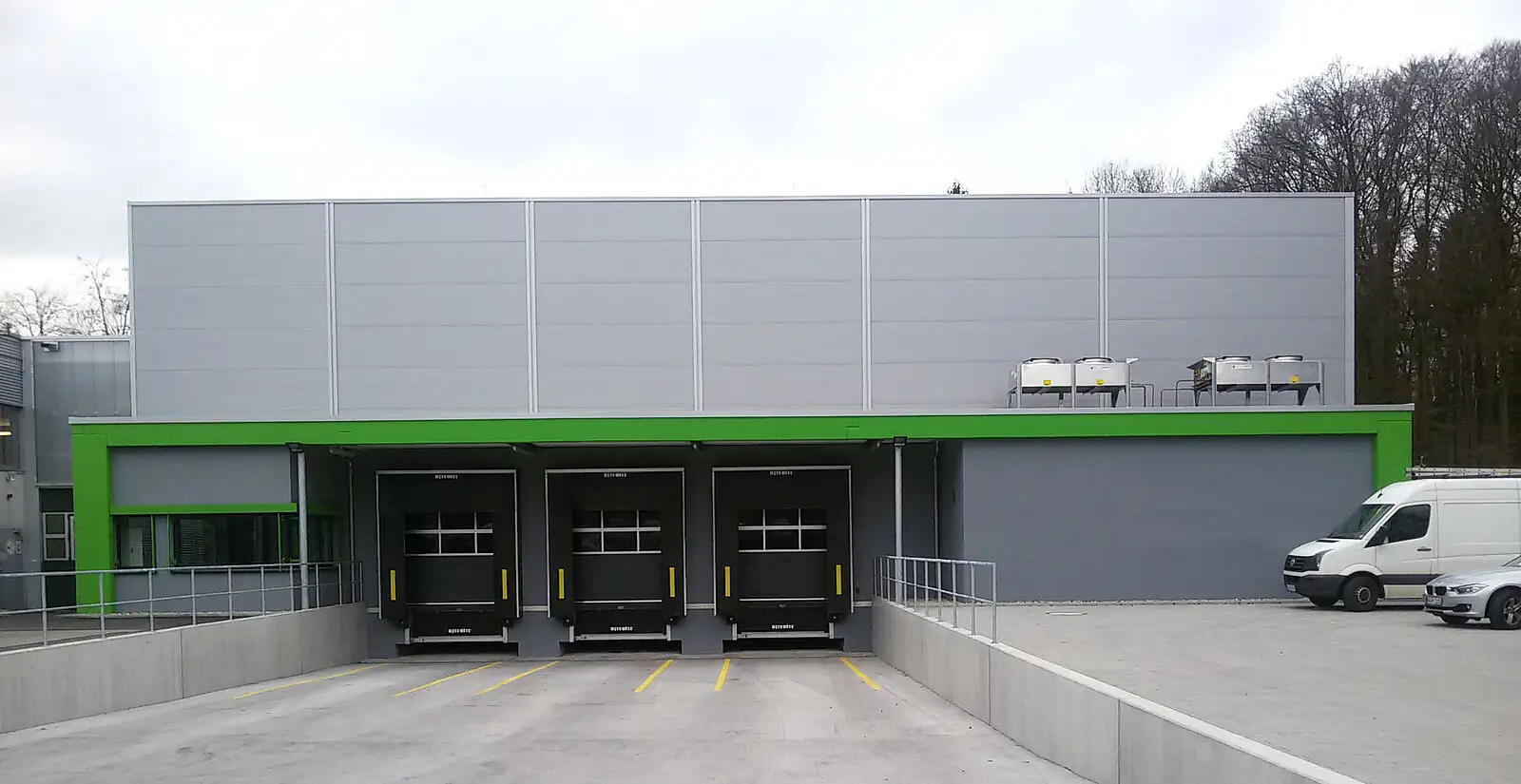 Außenansicht eines Kühlhauses mit mehreren grauen Sektionaltoren für LKW.