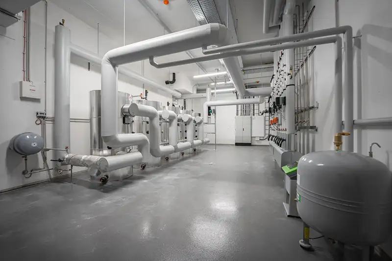 Großzügiger, heller Raum mit Rohrleitungen und technischer Ausstattung für industrielle Nutzung.