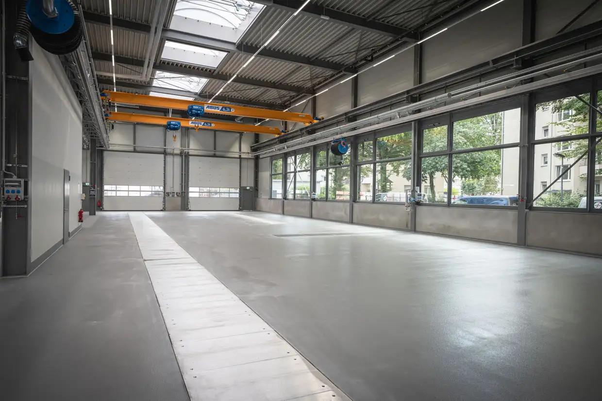 Große, lichtdurchflutete Montageshalle mit glänzendem Industrieboden für Gewerbe.