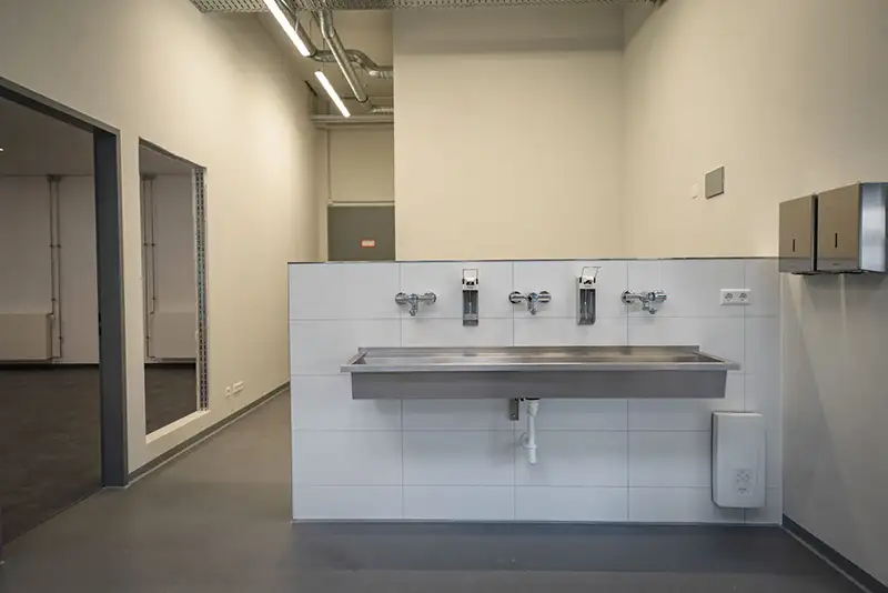 Moderner Waschbereich aus Edelstahl in den Sanitäranlagen eines neuen Industriegebäudes.