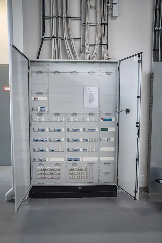 Offener Schaltschrank mit komplexer Elektrik in einem modernen Industriegebäude von PUR Projektbau.