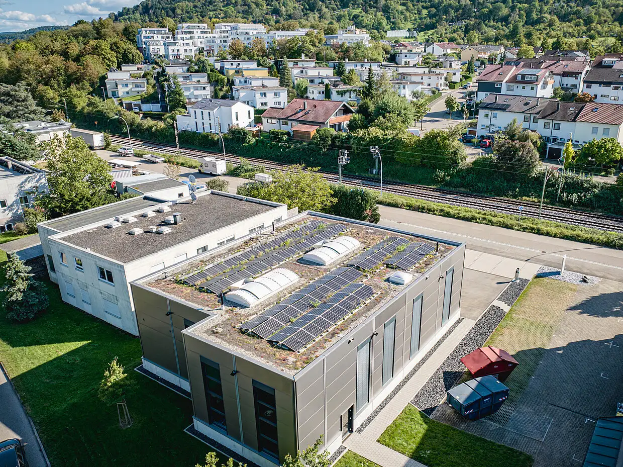 Luftaufnahme eines Gewerbebetriebs mit begrüntem Dach und Solarmodulen von PUR Projektbau.