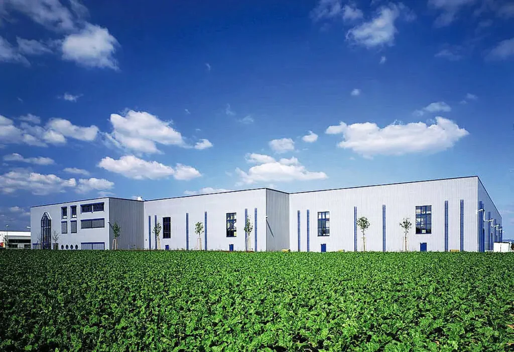 Moderne, baugleiche Gewerbehallen unter blauem Himmel von PUR Projektbau.