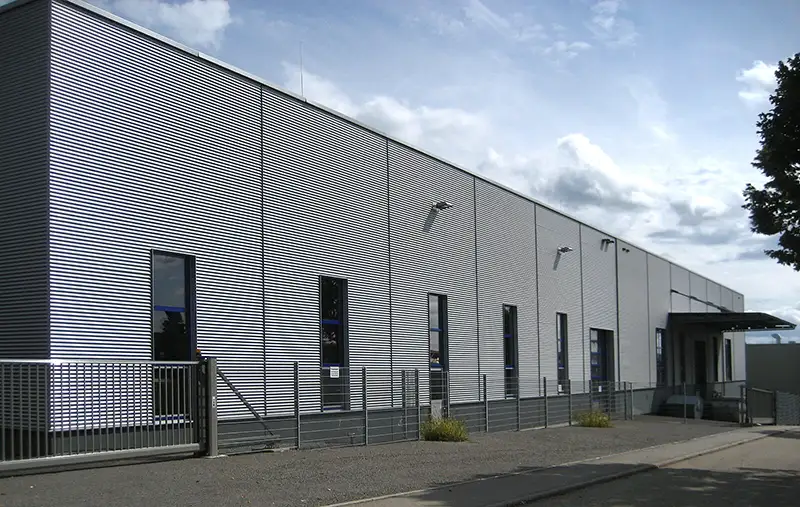 Langgestreckte Industriehalle mit minimalistischer weißer Fassade.