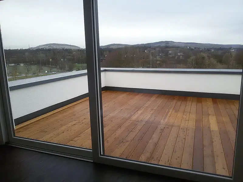 Moderne Terrasse eines Bürogebäudes mit Holzbeplankung und Blick ins Grüne.