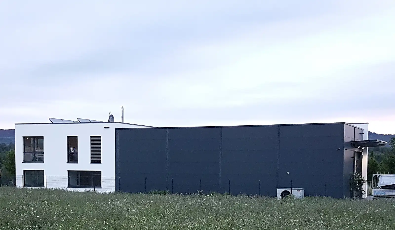 Schlichtes, dunkles Industriegebäude hinter einer Rasenfläche.