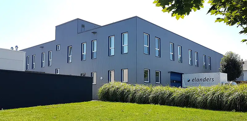 Elegantes, graues Druckereigebäude mit gepflegtem Rasen davor.