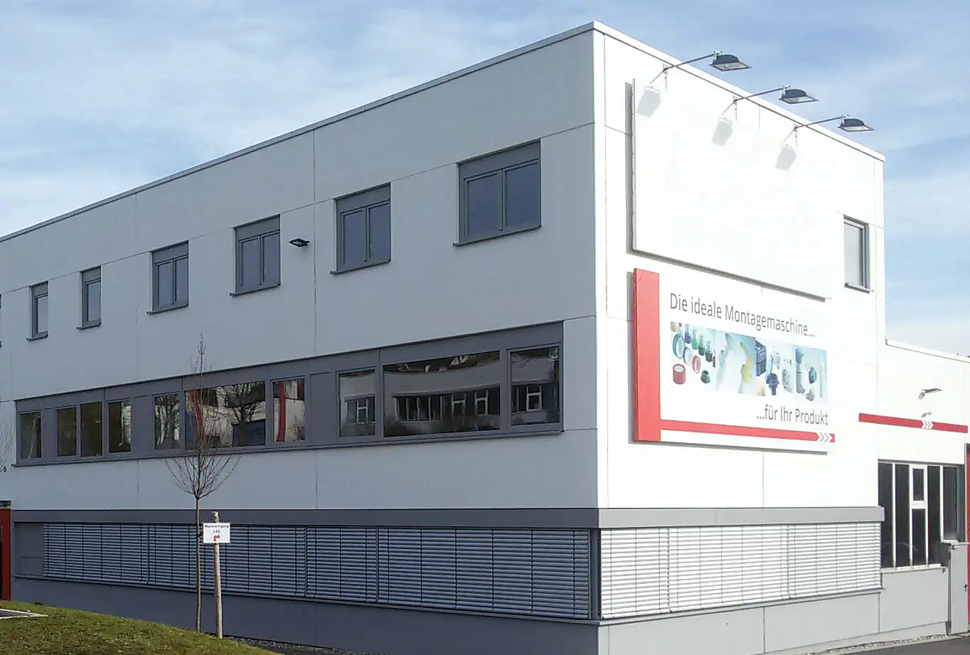 Großes weißes Bürogebäude mit Fensterfronten und Platz für Firmenlogos.
