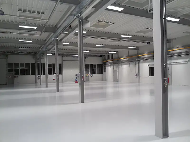Innenansicht einer riesigen, bezugsfertigen Produktions- oder Lagerhalle mit Betonboden.